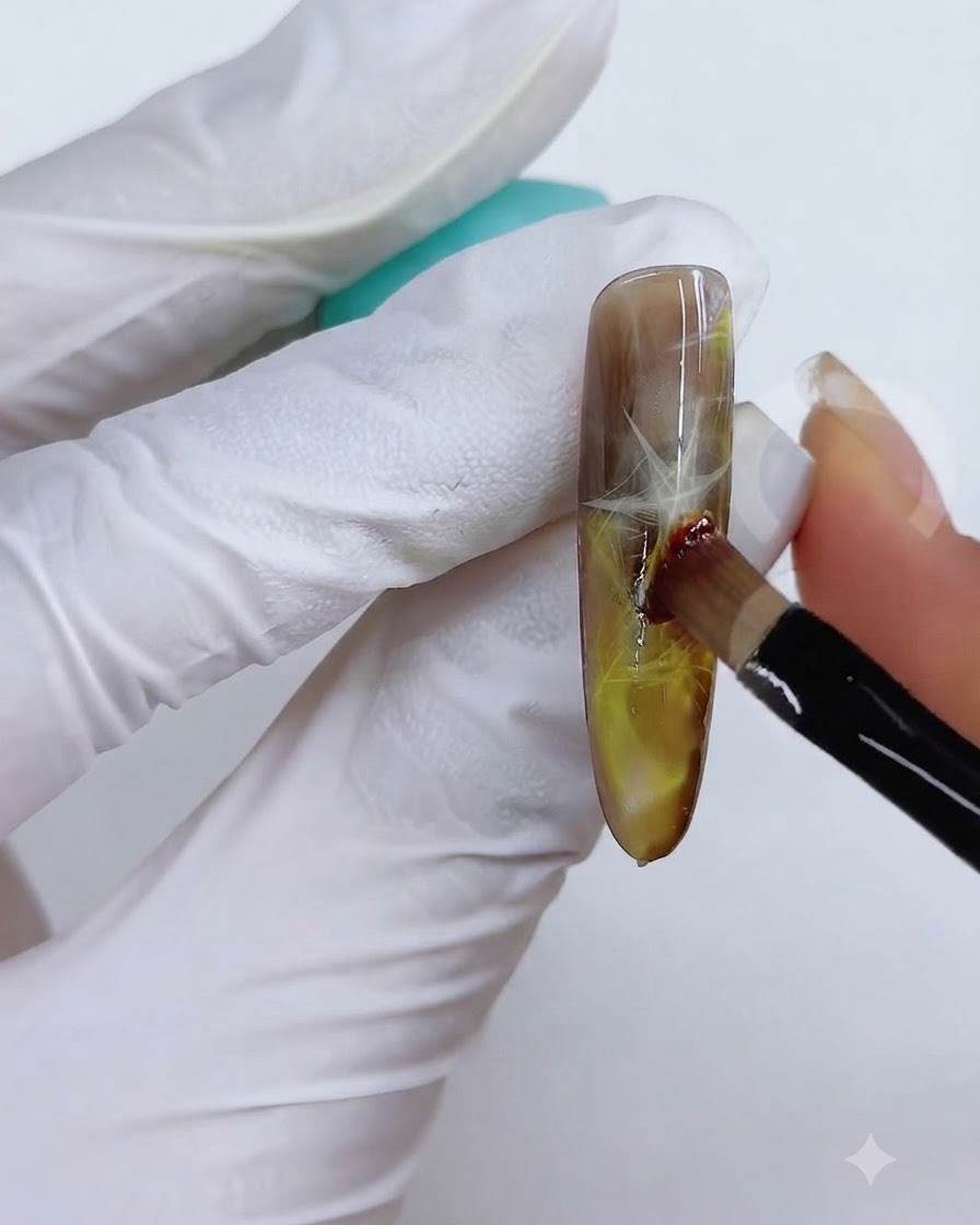 Une technique de pinceau et déponge utilisée pour estomper la couleur jaune-brune sur la surface de longle.