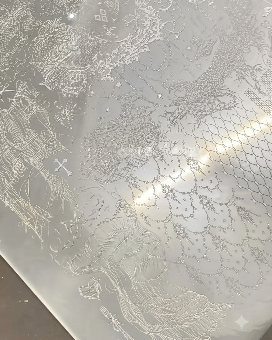 Un tampon transparent pressé sur une plaque de stamping en métal remplie de motifs de dentelle blanche complexes.