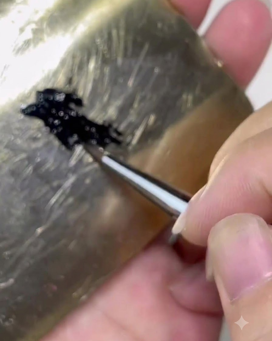 Un pinceau chargeant du gel noir depuis une palette sur environ un tiers du corps du pinceau.