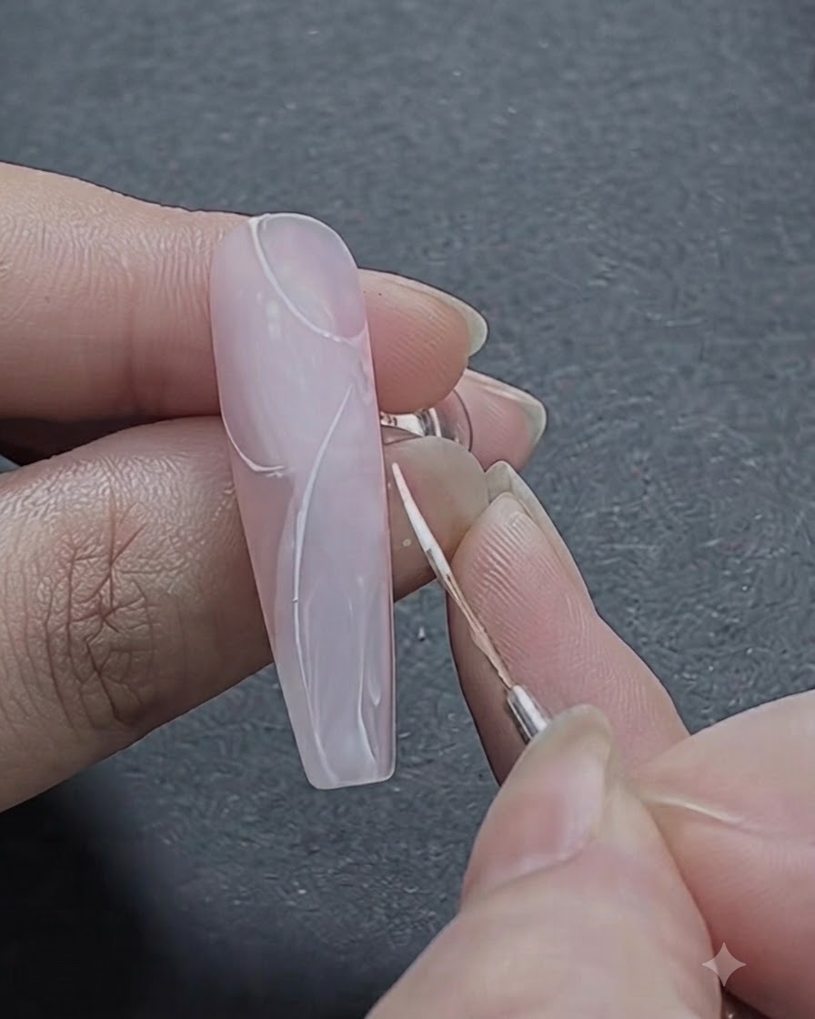 Un pinceau fin esquissant les premiers traits blancs incurvés d un motif de rose sur la section supérieure de l ongle.