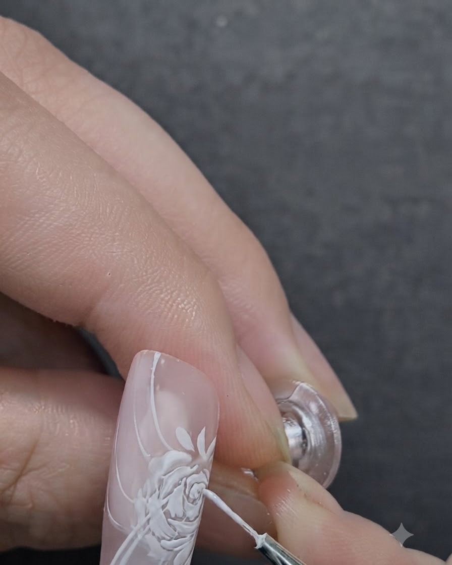 Une prothésiste ongulaire appliquant du gel de modelage 3D au centre d une rose peinte à l aide d un pinceau de détail.