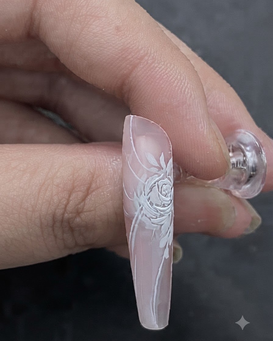 Une image rapprochée montrant une nuance de rose clair appliquée au pinceau sur le centre d un design d ongle de rose blanche en relief.
