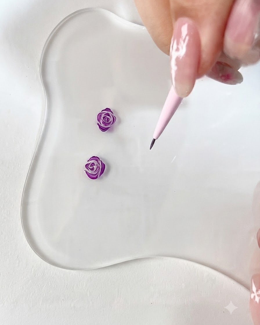 Une vue rapprochée dun pinceau liner fin dessinant un petit crochet courbé violet sur une palette transparente.