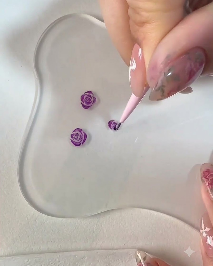 Un pinceau liner fin peignant des pétales supplémentaires le long du contour inférieur du nail art de rose violette.