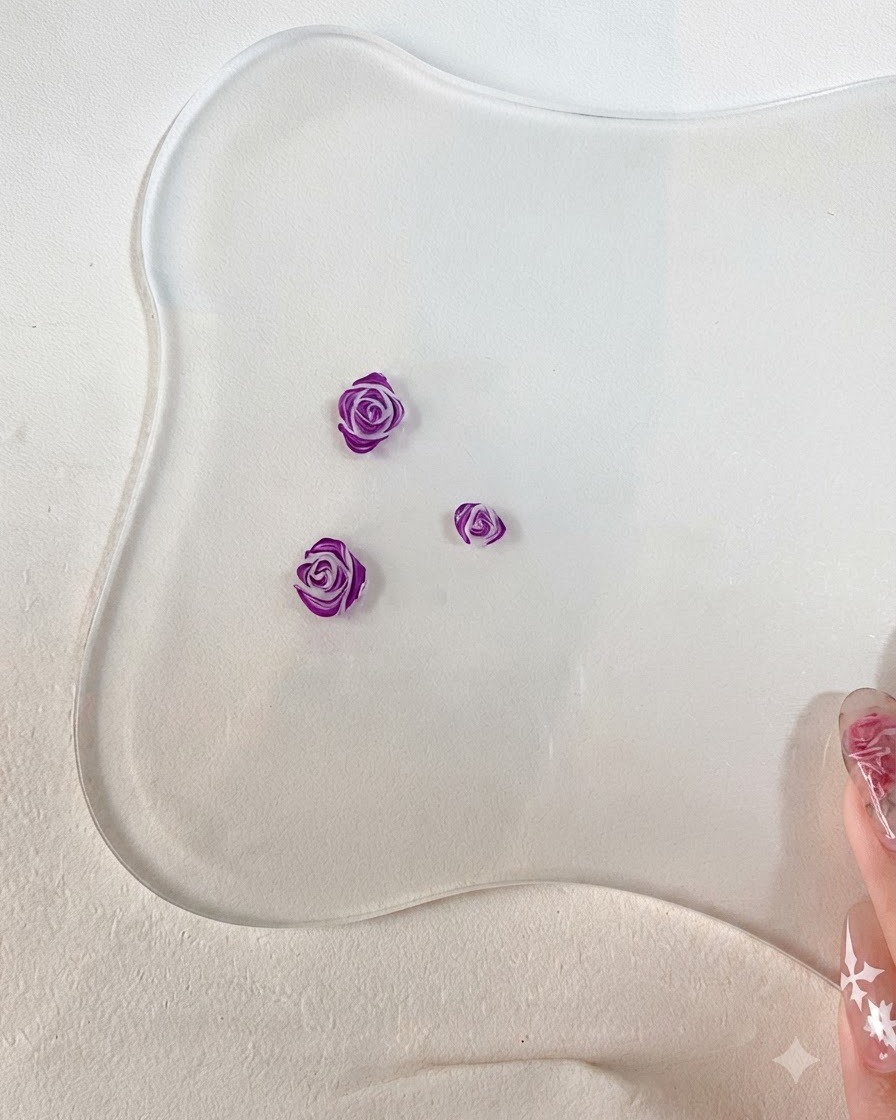 Un gros plan dun pinceau fin de nail art ajoutant des contours violet foncé détaillés sur les bords des pétales de rose 3D sculptés.