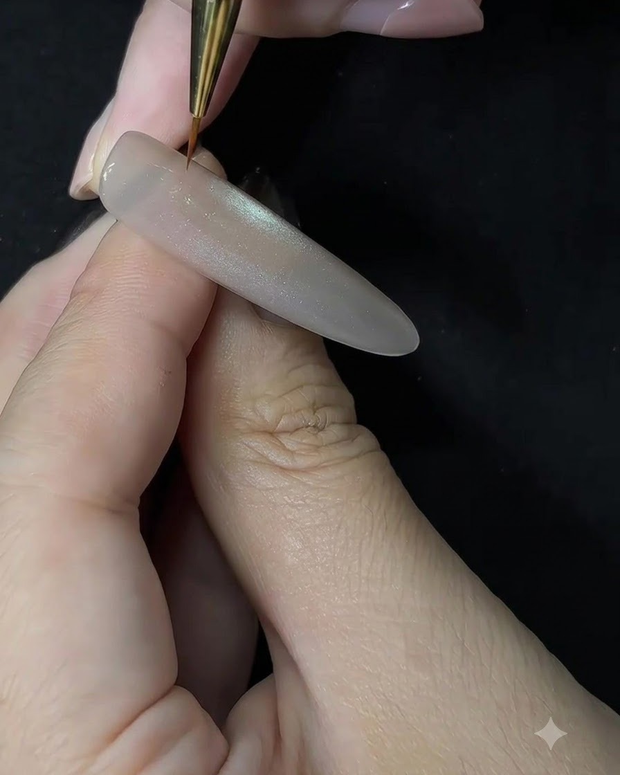 Gros plan dune prothésiste ongulaire utilisant un pinceau fin pour appliquer du gel blanc par tapotement sur une extension sculptée.