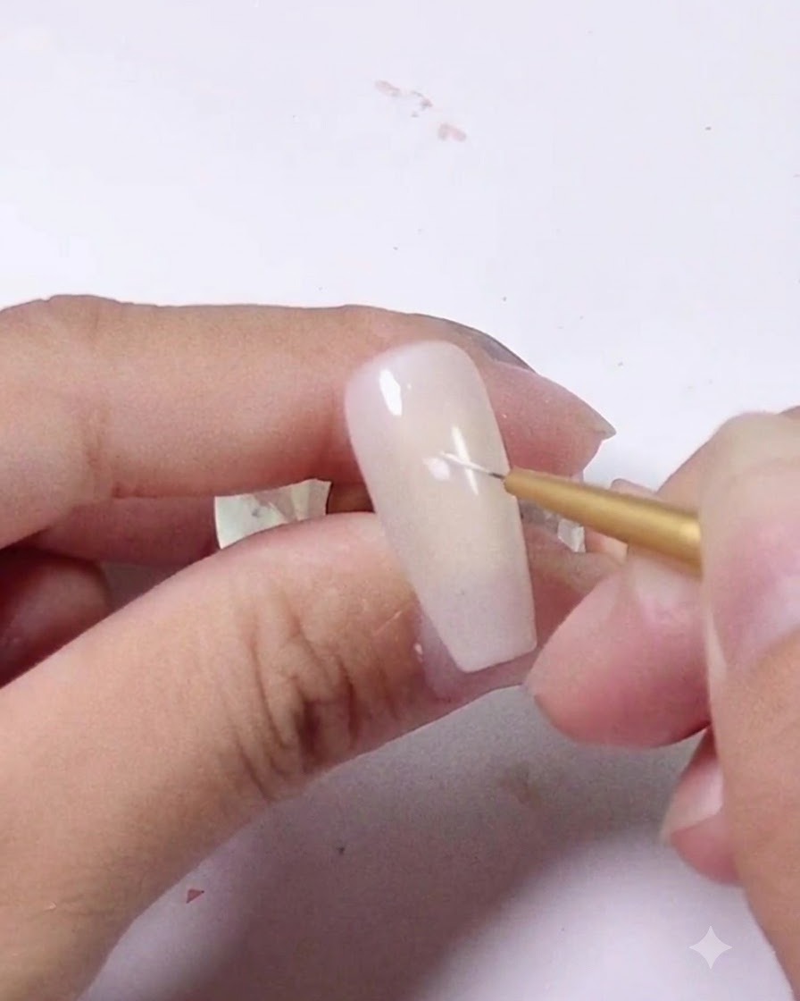 Gros plan dun pinceau fin appliquant un petit trait blanc sur un ongle rose clair.