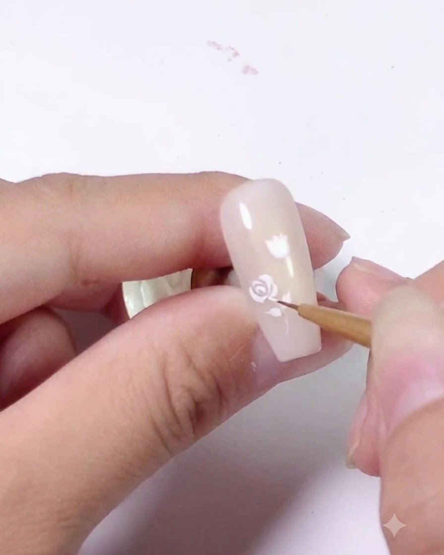 Motif de rose blanche terminé, peint sur la moitié supérieure dun ongle rose clair.