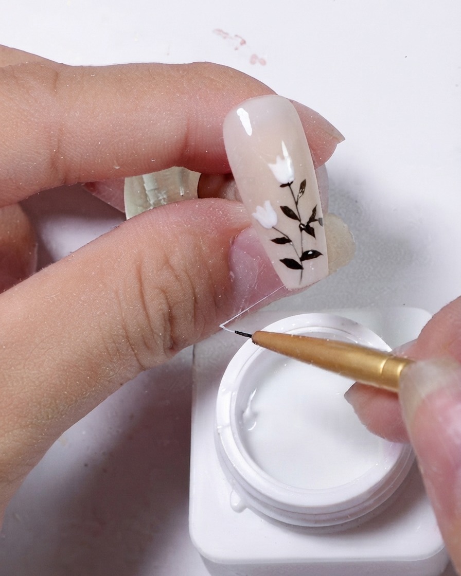 Ongle en cours de décoration avec un fil élastique de gel blanc drapé en diagonale sur la surface.