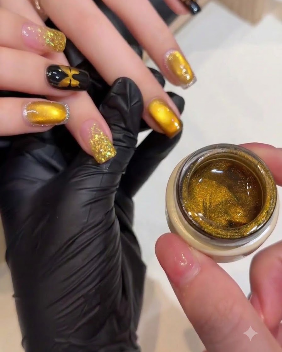 Une prothésiste ongulaire utilisant un petit aimant pour façonner les particules scintillantes sur un ongle cat-eye doré.