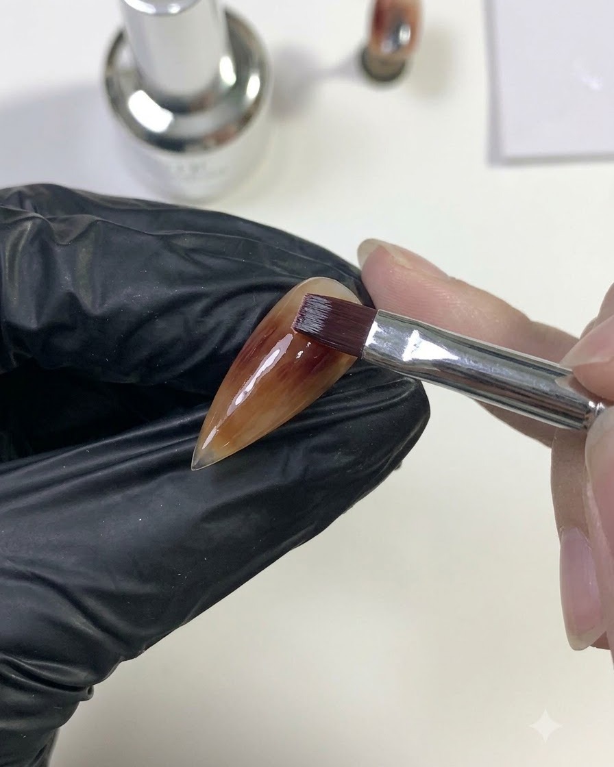 Un pinceau mélangeant le gel rouge profond vers lextérieur pour fusionner avec la couche de base caramel.