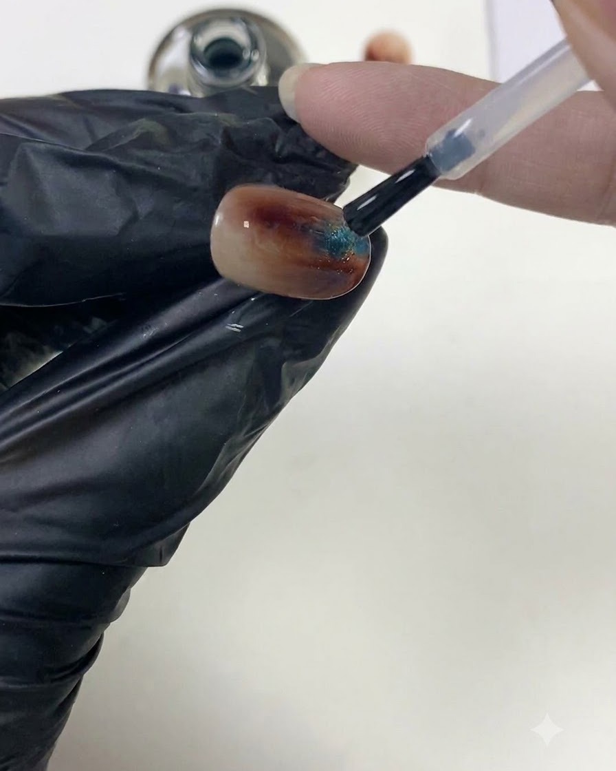 Un pinceau à ongles lissant le top coat transparent sur une surface dongle ambre texturée pour façonner lapex.