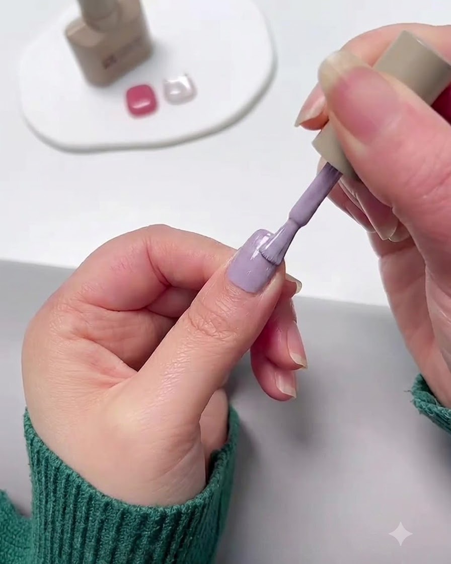 Un pinceau à ongles appliquant du vernis en gel violet lavande sur un ongle.