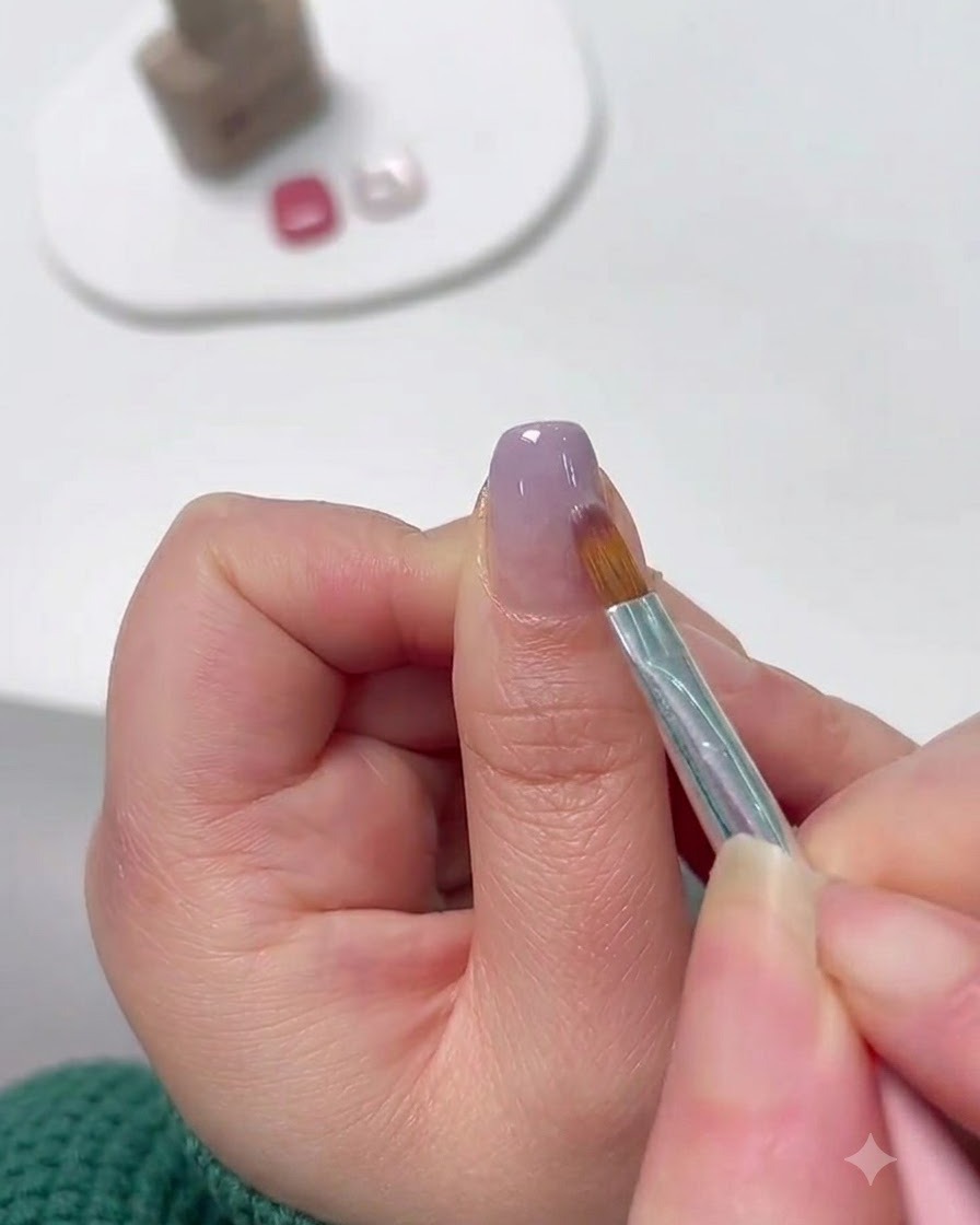 Un pinceau fin pour nail art étirant le gel lavande de lextrémité vers le haut pour former un dégradé.