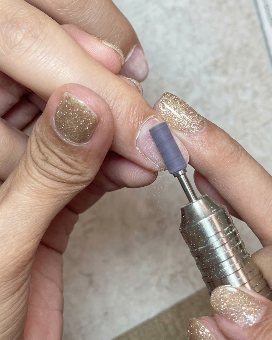 Un manchon de ponçage sur une ponceuse électrique polissant délicatement la surface dun ongle naturel.