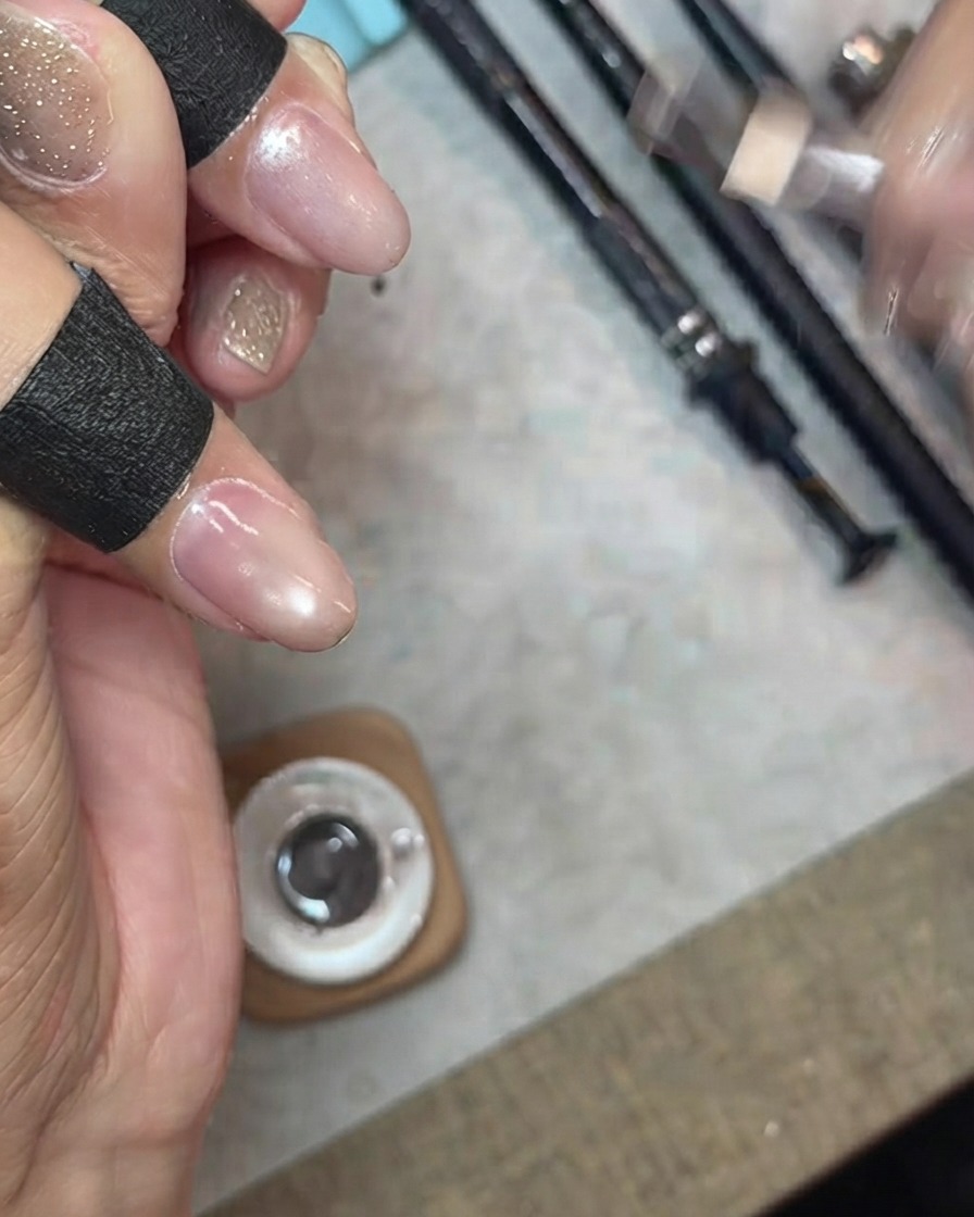Application dune couche de gel cat-eye scintillant fin et transparent sur un ongle.