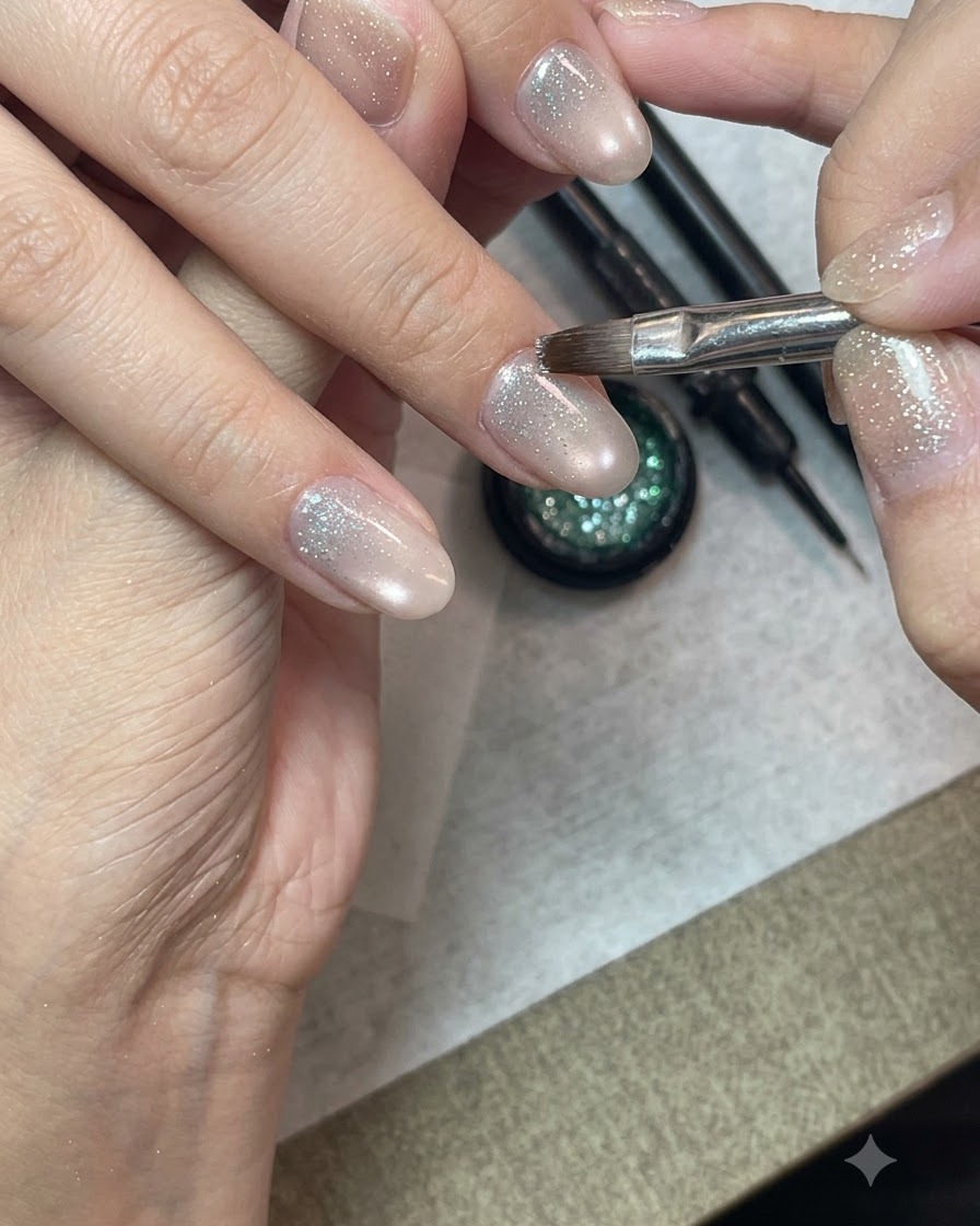 Un pinceau de nail art détaillé appliquant du gel pailleté crushed diamond sur la moitié inférieure dun ongle préparé.
