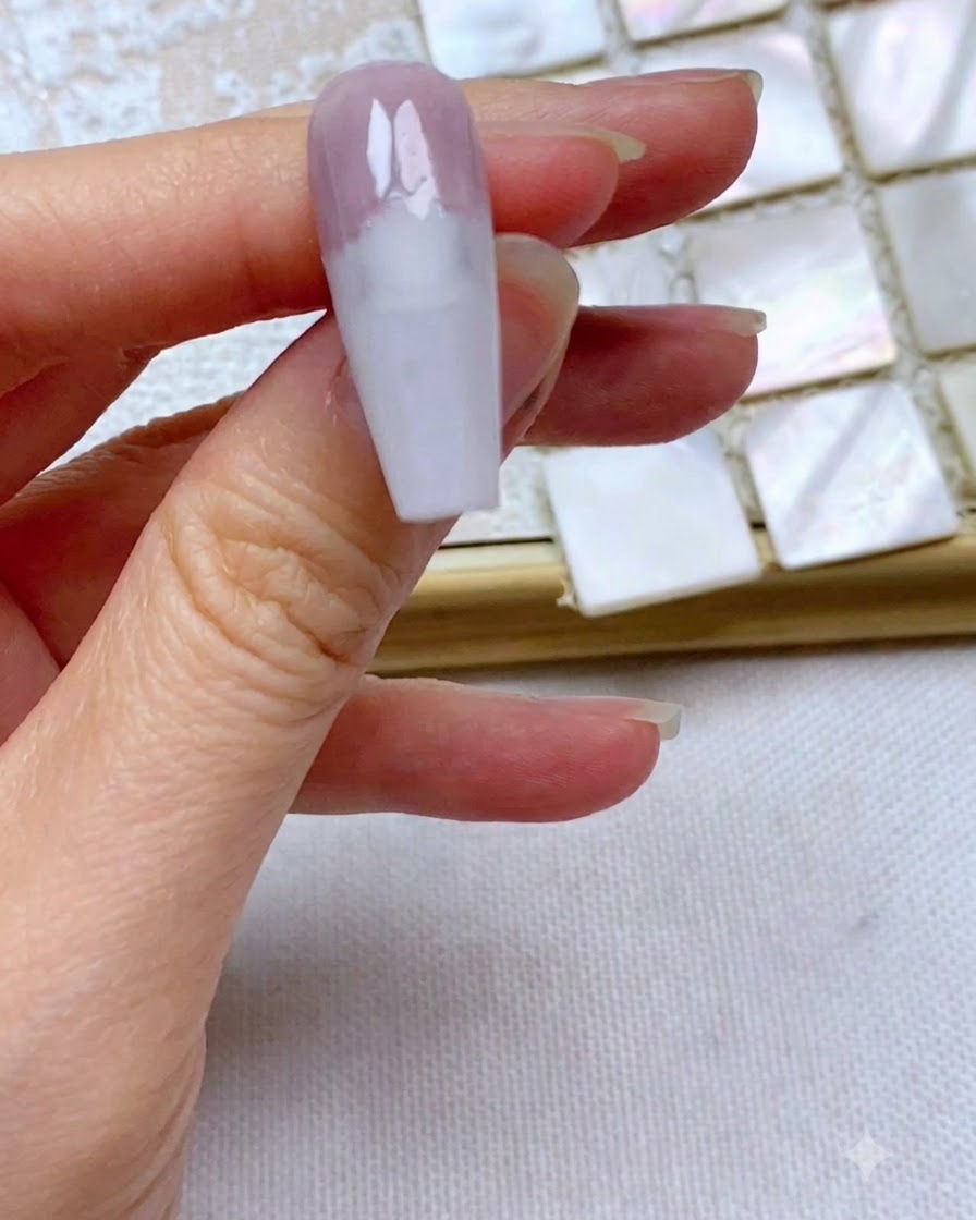 Un ongle montrant un bord de gel gris-violet parfaitement droit et net appliqué sur le tiers supérieur.