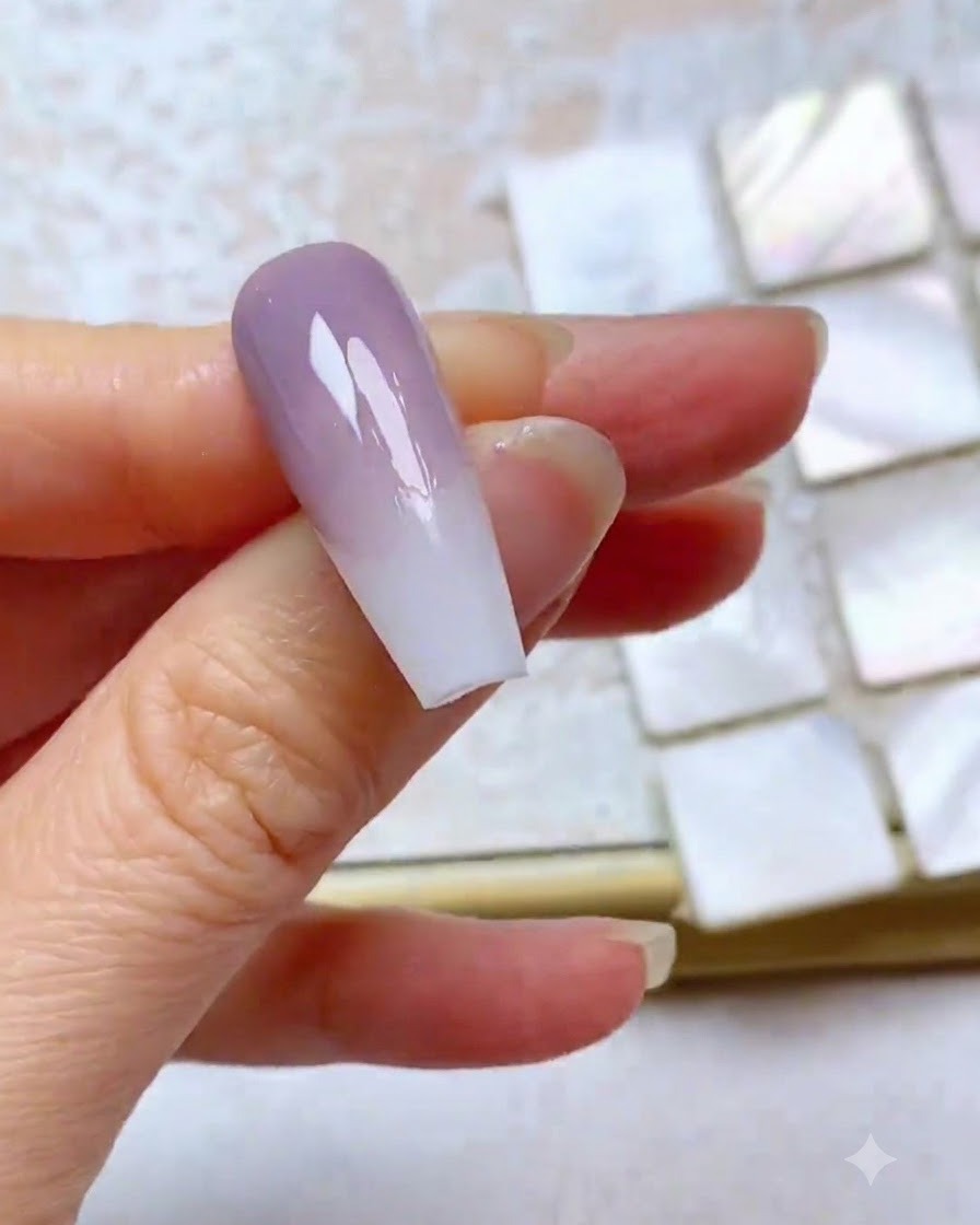 Un ongle montrant une troisième couche de gel violet estompée avec un bord supérieur net.