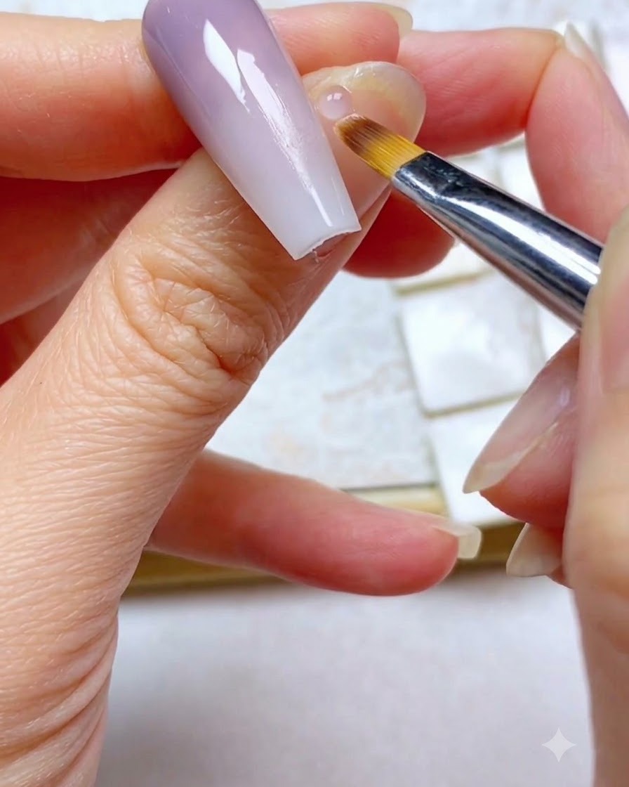 Gros plan dun pinceau ombré balayant légèrement la section violette supérieure dun ongle en dégradé.