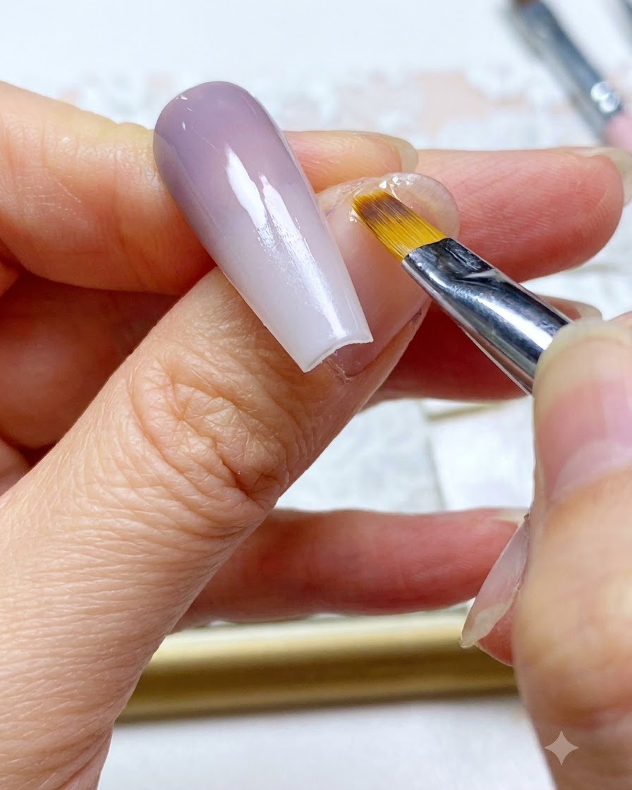 Un pinceau à ongle effectuant un balayage de retouche final le long de la section de couleur estompée de longle.