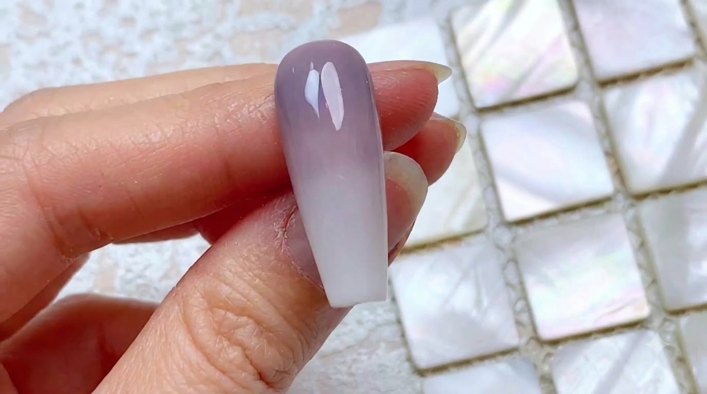 Gros plan dun ongle avec un dégradé vertical bicolore terminé, passant dun gris-violet poussiéreux au niveau des cuticules à un blanc laiteux sur le bord libre.