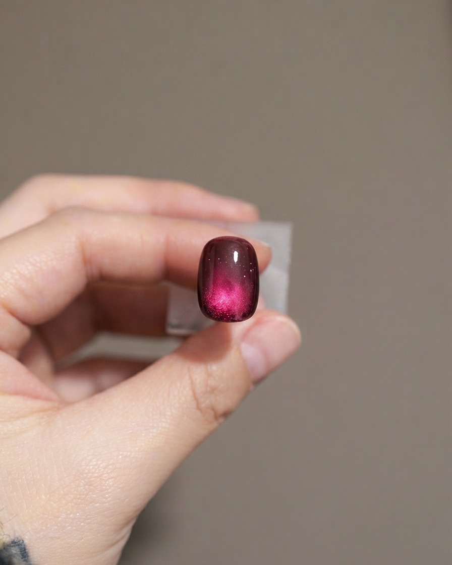 Un ongle montrant une seconde couche de vernis gel cat-eye violet foncé.