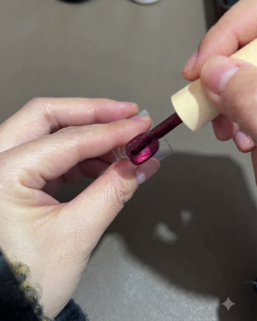 Un pinceau lissant une deuxième couche de vernis gel cat-eye violet sur un support dongle.