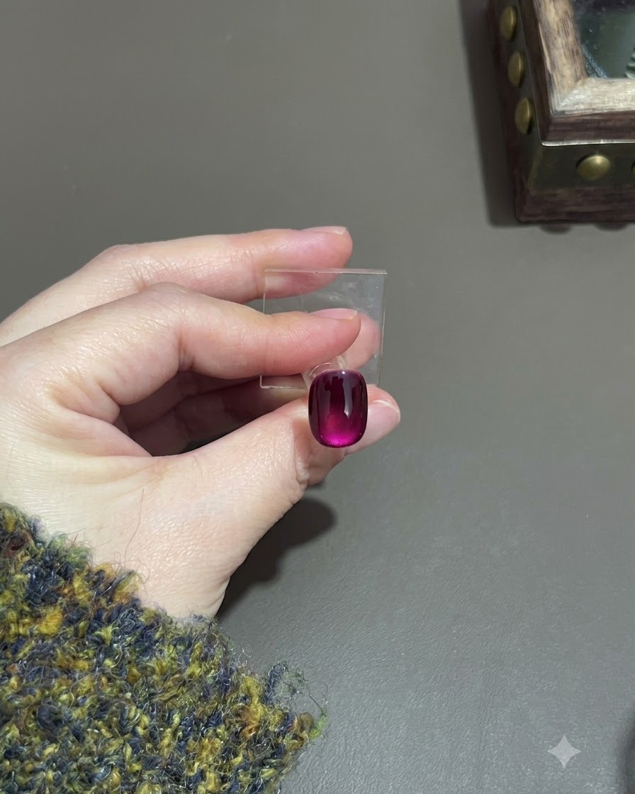 Un ongle cat-eye violet catalysé montrant un effet de dégradé profond sur un support de présentation.