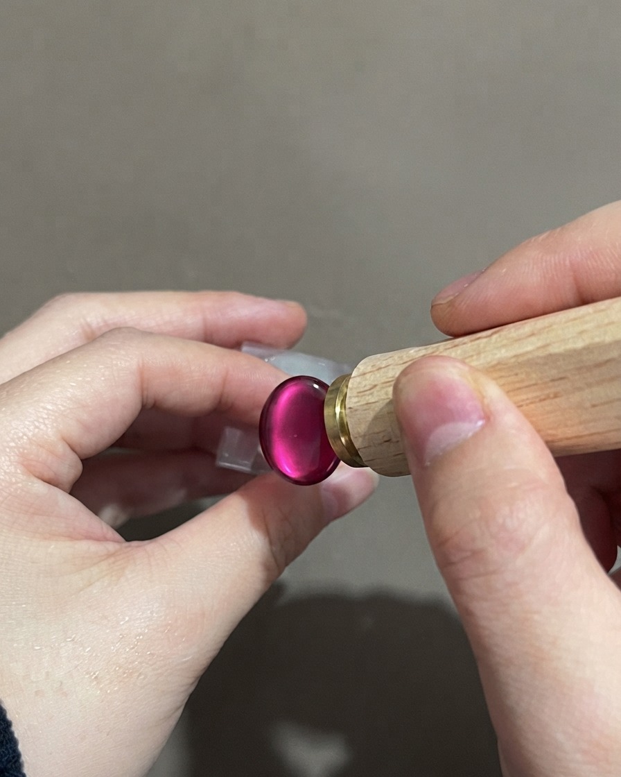 Une main tenant un outil de stamping près dun ongle cat-eye dégradé violet terminé.