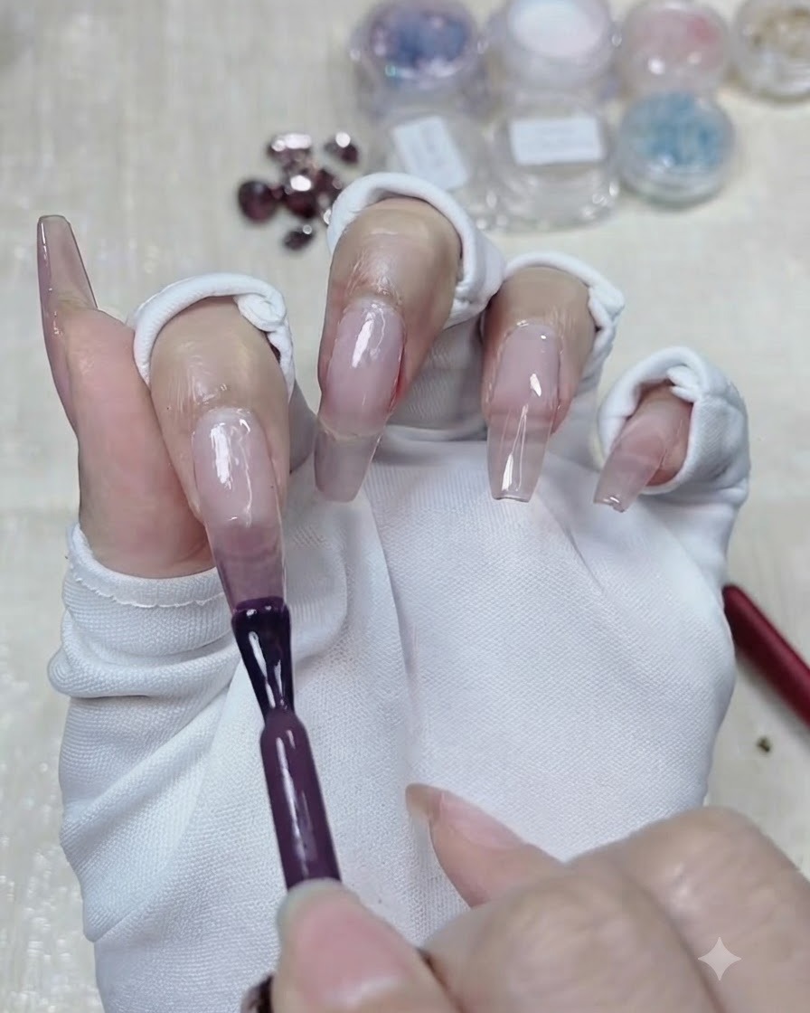 Un pinceau appliquant une deuxième couche plus profonde de gel violet taro sur la moitié supérieure de longle.