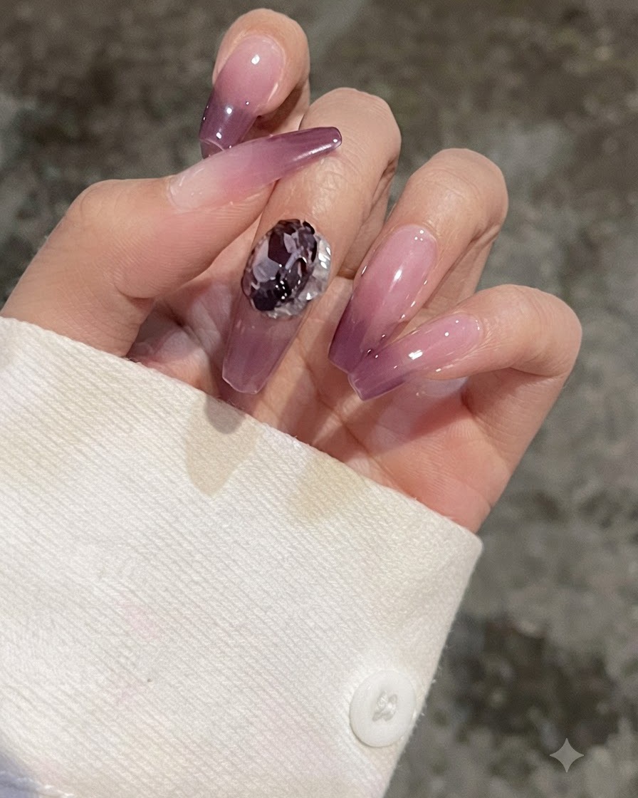 Gros plan dun doigt avec un ongle en dégradé violet montrant une gemme en forme de cœur placée pour comparaison.