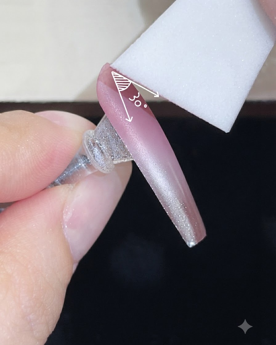 Une éponge en mousse appliquant une seconde couche de gel de couleur sur un ongle nude dégradé avec un angle contrôlé.