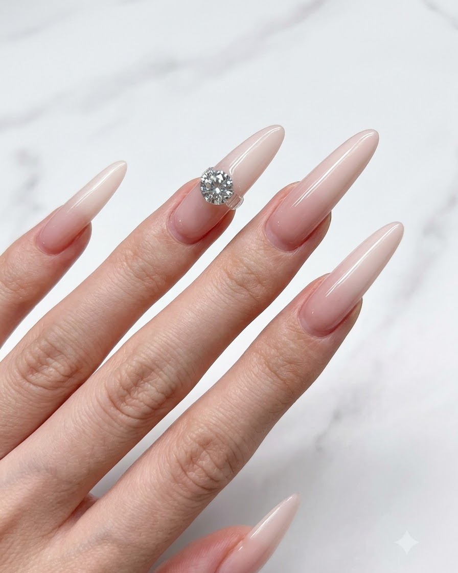 Un pinceau à ongles appliquant une fine couche de base nude translucide sur un long ongle stiletto.
