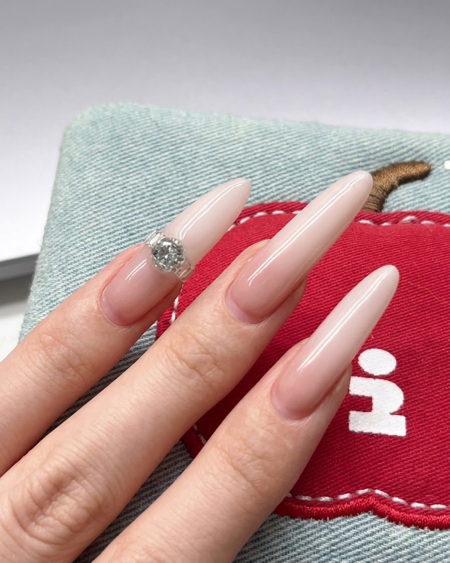 Gros plan dun pinceau à ongles appliquant un pigment gel blanc sur le bout dun long ongle stiletto nude.