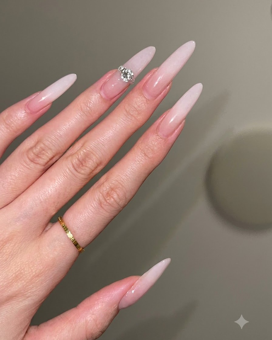 Une prothésiste ongulaire utilisant un pinceau dans un mouvement de tapotement doux pour créer un dégradé ombré blanc laiteux sur une base nude.