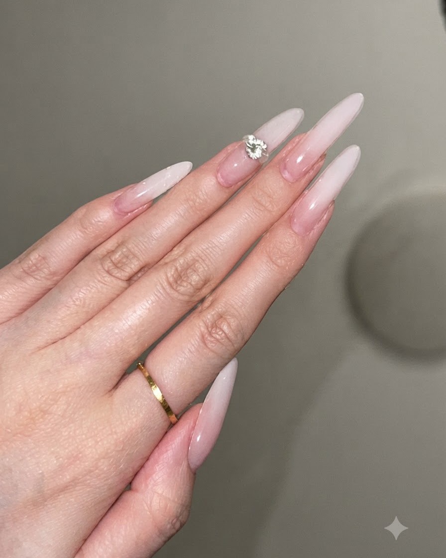 Une goutte dadhésif en gel transparent posée au centre dun ongle stiletto décoré.