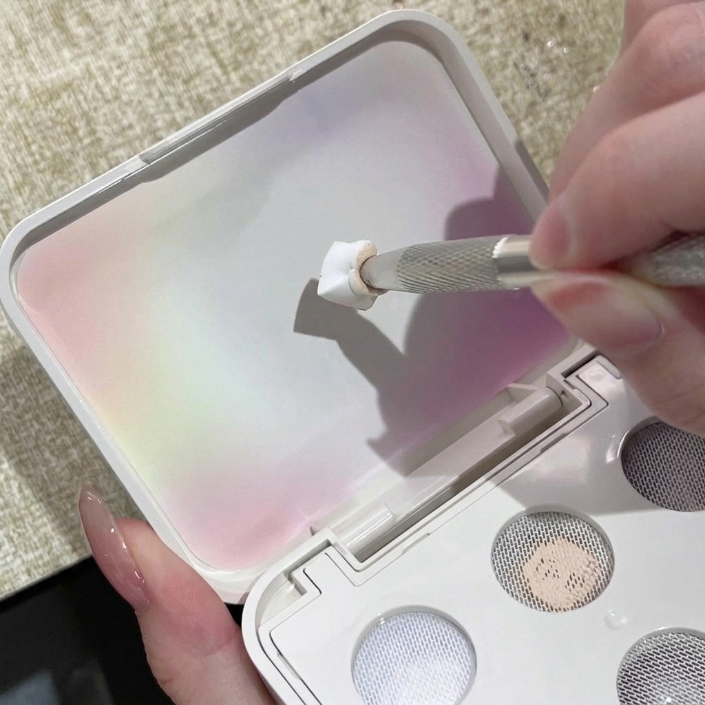 Un outil à ongles en métal pressant du gel solide blanc sur la surface texturée du couvercle de la palette.