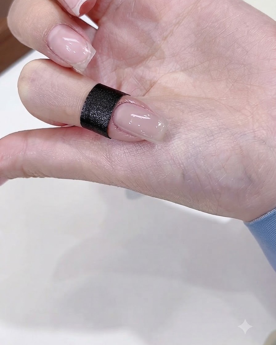 Gros plan sur un onglet peint avec une couche de base gel nude brillante.