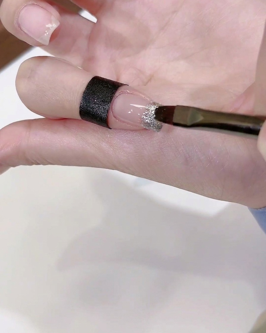 Un pinceau appliquant une noisette de colle diamant transparente sur une pointe dongle décorée.