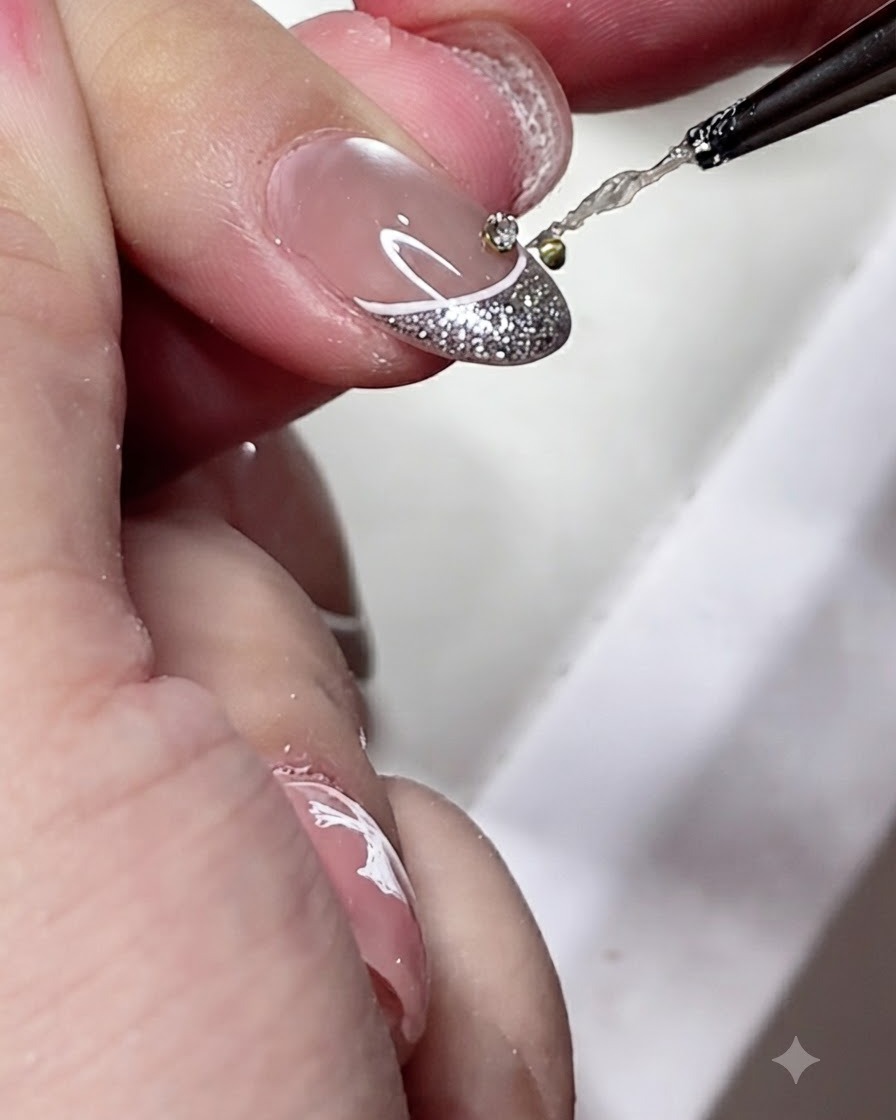 Un pinceau de détail appliquant une petite goutte de gel adhésif transparent au centre dune pointe de french manucure décorée.