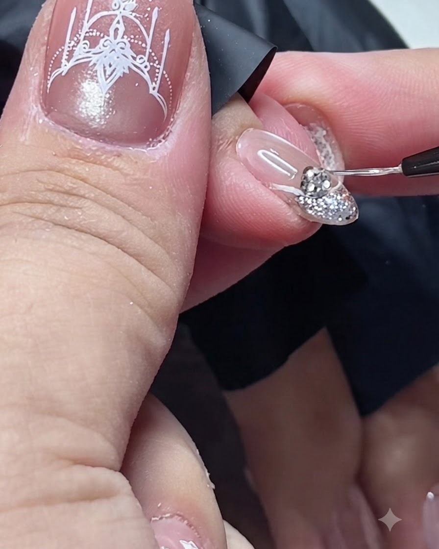 Un pinceau de détail fin appliquant du top coat autour de la base dun strass sur un ongle.