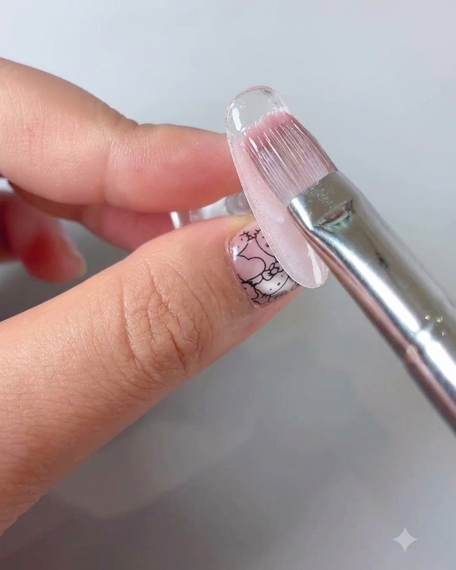 Un pinceau de manucure appliquant un top coat de scellement transparent sur un design dongle floral.