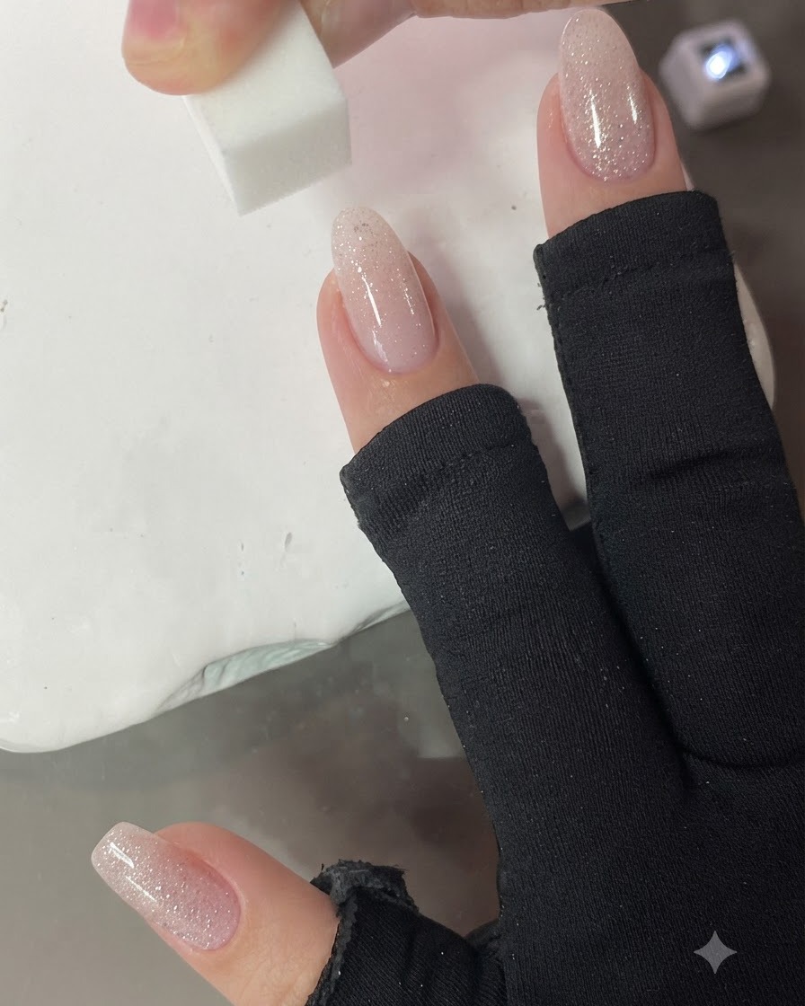 Une petite éponge tapotant verticalement sur longle pour estomper le dégradé rose nude.