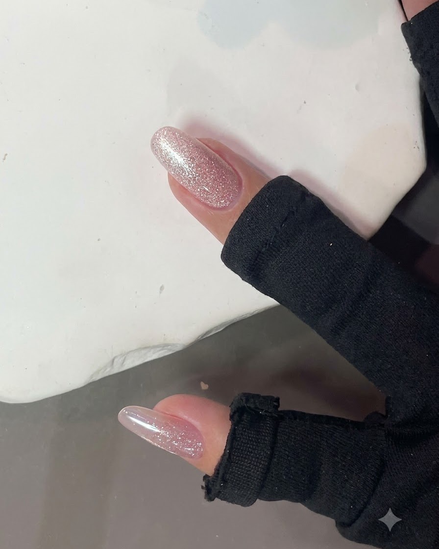 Un aimant à ongles puissant maintenu près dun ongle rose pailleté brillant pour former un effet lumineux cat-eye.