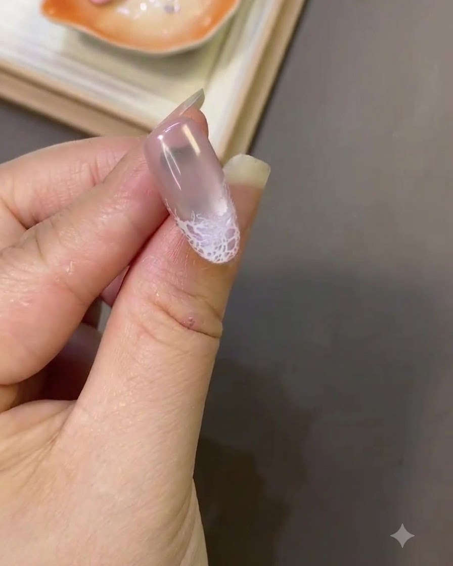 Gros plan dun ongle montrant un design en dentelle blanche terminé près du bout avec une texture de surface lisse.