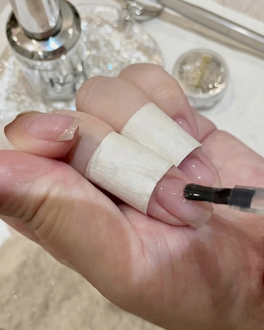 Gros plan de la pose dun grand cristal rectangulaire sur un ongle avec de ladhésif.