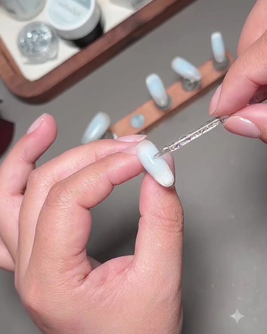 Un pinceau nail art fin appliquant une deuxième couche de gel bleu pour assombrir le centre de longle.