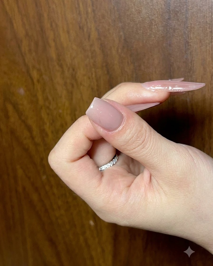 Une main tenant un ongle doté dune couche de base nude terminée, vue de profil pour vérifier luni.