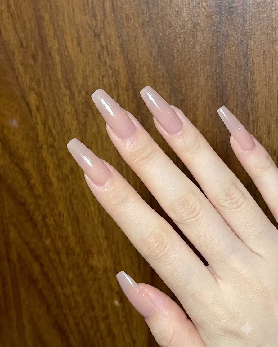 Aperçu dune main présentant de multiples ongles en the acrylique longs et brillants aux tons nude.